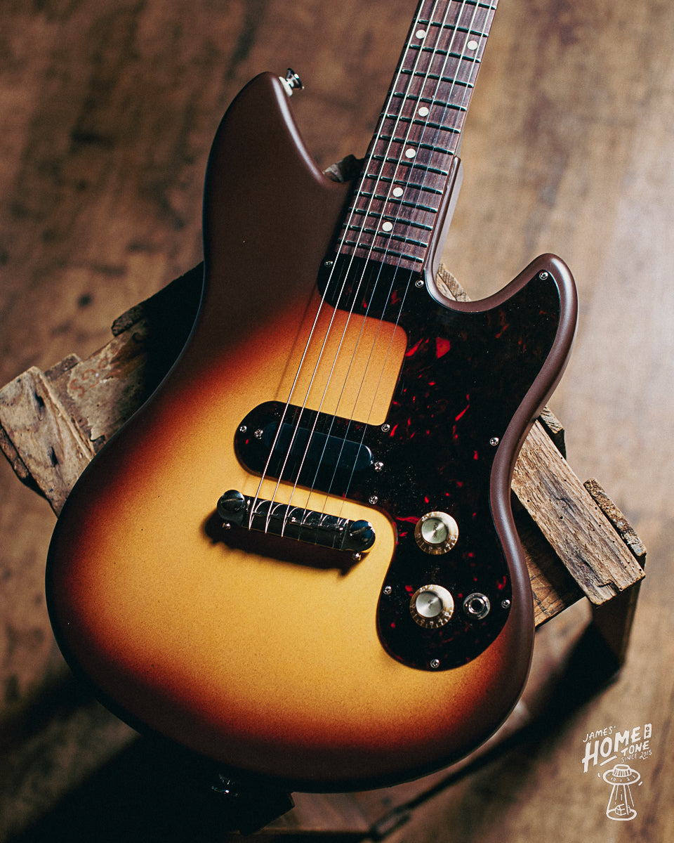A Lovalet Crossroad guitar with a vintage brown sunburst finish, dark stain mahogany body, and a tortoise pickguard.