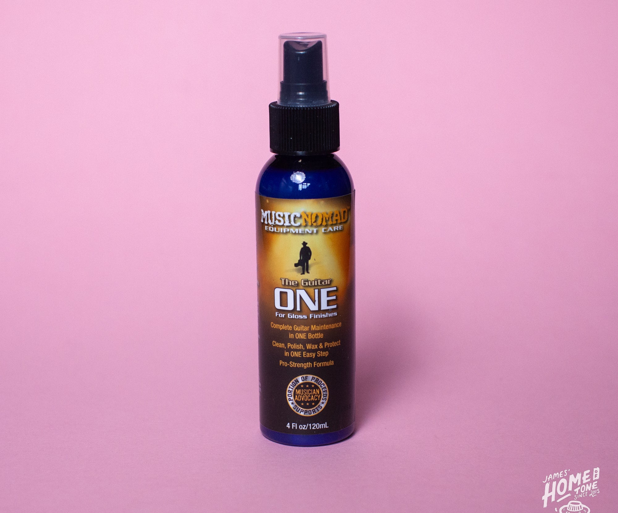 A spray bottle labeled 'Guitar ONE' by MusicNomad, designed for cleaning, polishing, and waxing gloss finishes on guitars. The bottle is on a pink background.