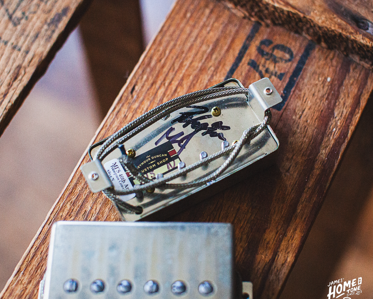 Guitar pickups signed by Peter Frampton on a wooden surface with a blurred background