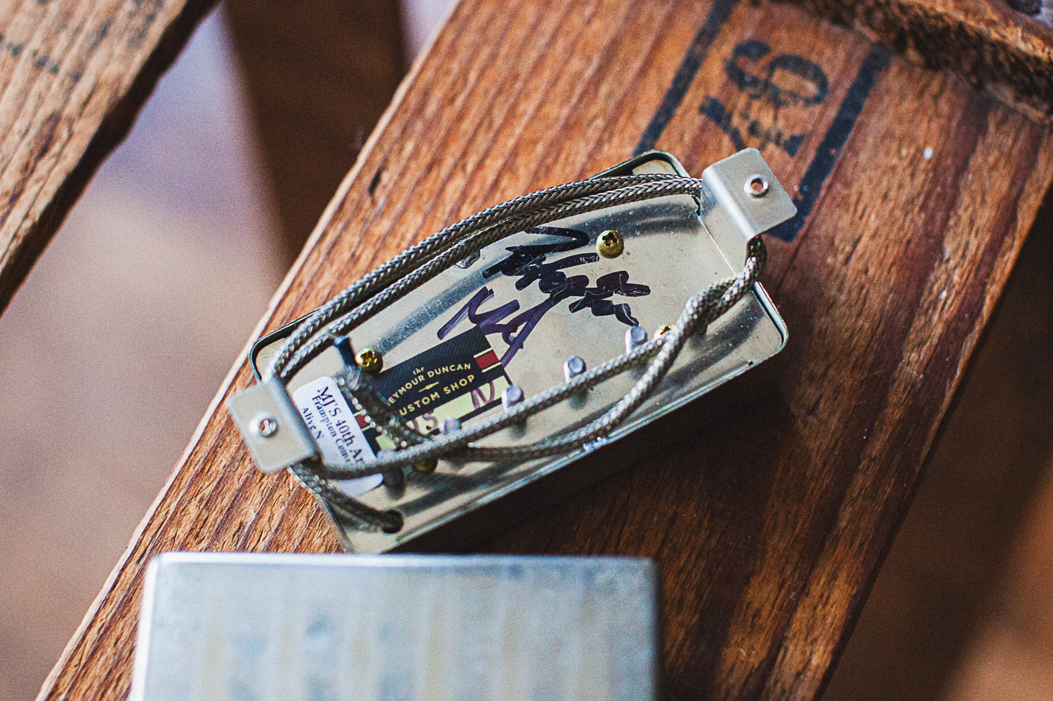 Guitar pickups signed by Peter Frampton on a wooden surface with a blurred background