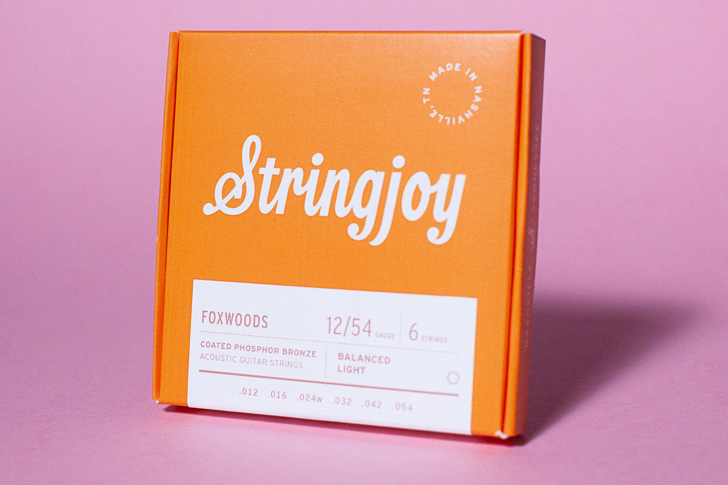 An orange box of Stringjoy Foxwoods coated phosphor bronze acoustic guitar strings with the text 'Stringjoy' and 'Foxwoods' on the front.