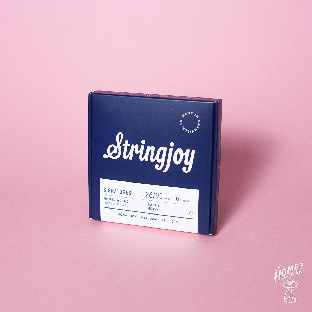 A box of Stringjoy Signature nickel wound electric bass guitar strings with gauges 26-95 displayed on a pink background.