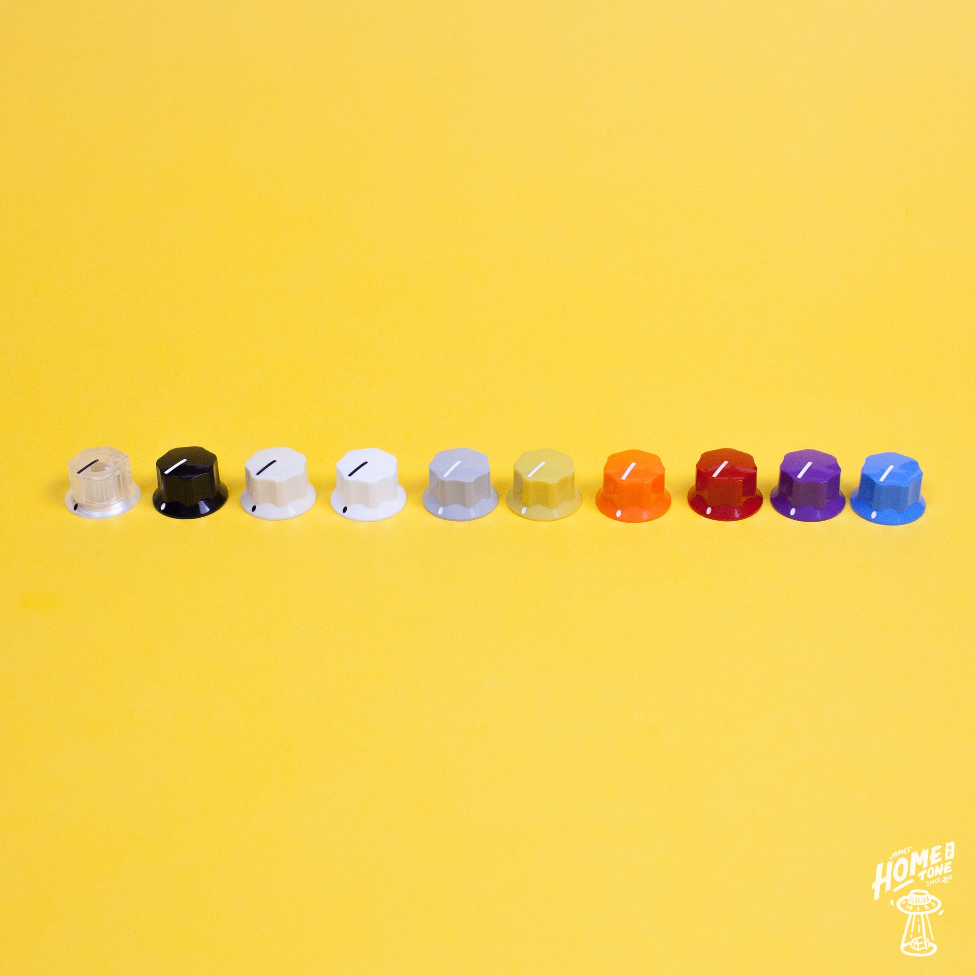 A selection of colored skirted control knobs arranged in a line on a yellow background, designed to fit 1/4" shaft pots.
