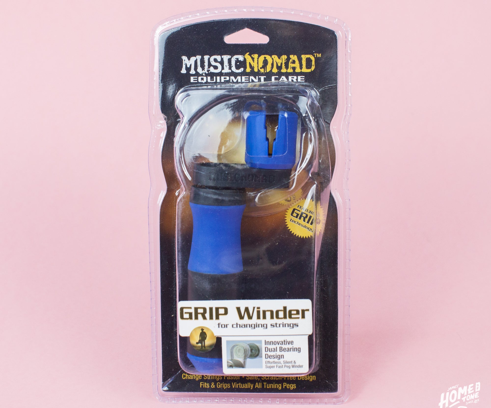 Packaged MusicNomad GRIP Winder with a blue handle, displayed in its clear plastic packaging, against a pink background.
