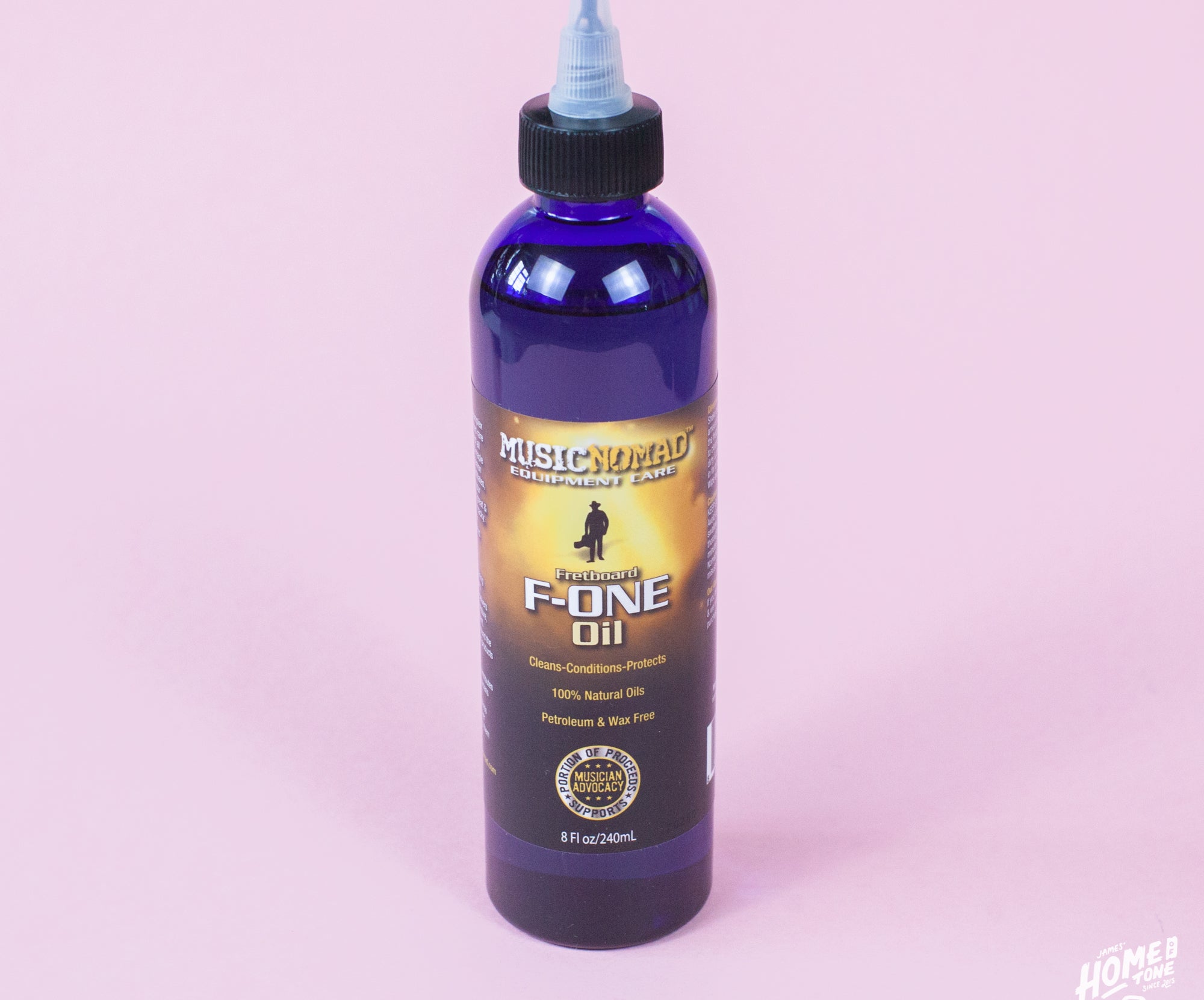 A bottle of MusicNomad Fretboard F-One Oil Cleaner & Conditioner with a blue label on an pink background.