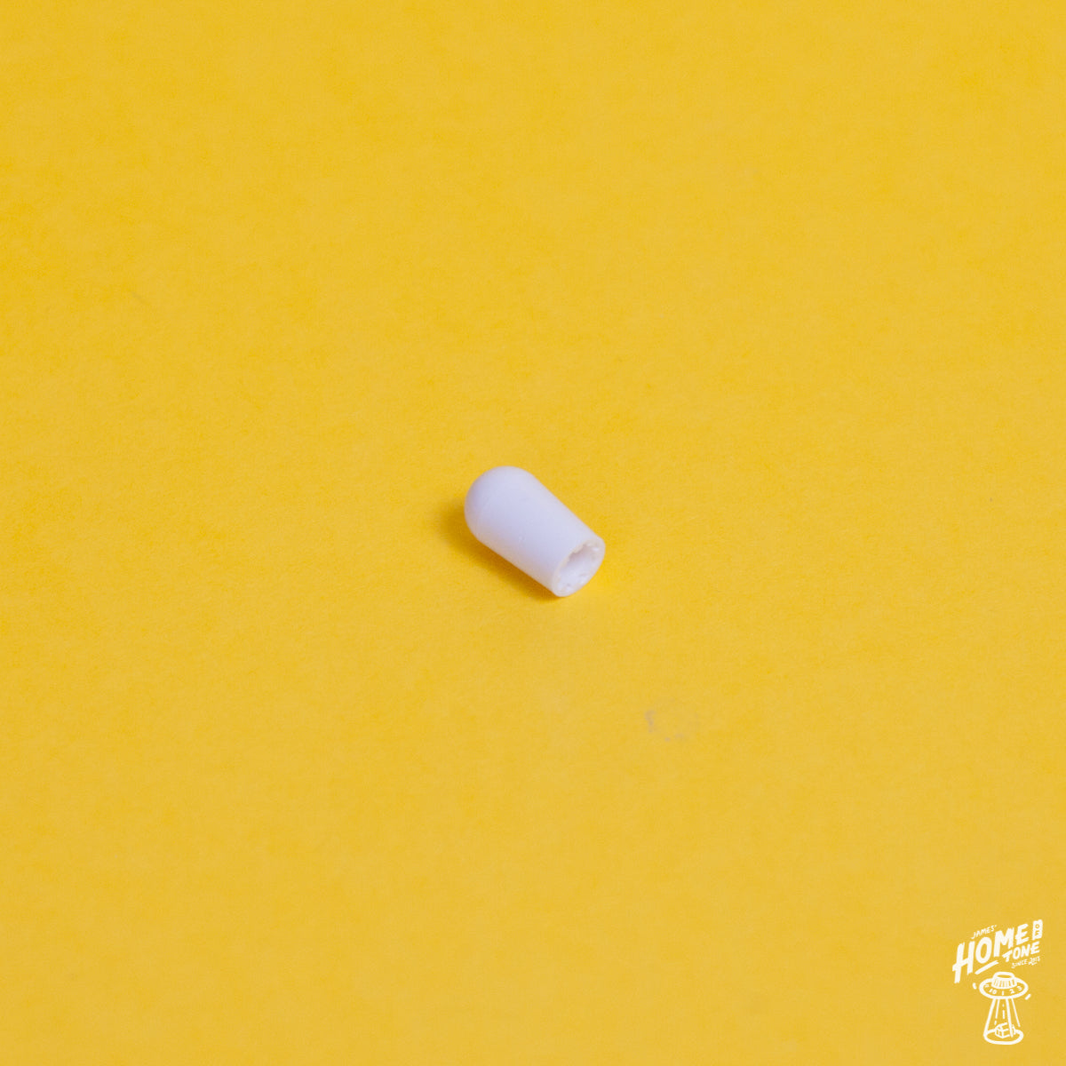 White switchcraft toggle switch tip placed on a yellow background with the Home of Tone logo in the corner