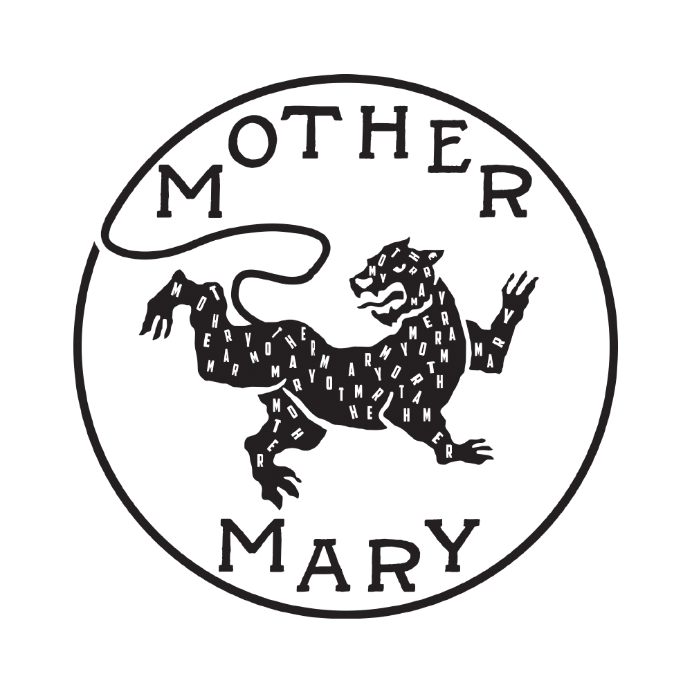 Flat lay photograph of a 'Mother mary Company' brand guitar strap, on a pink background with a boutique guitar, plectrums and a vinyl album lay out next to it.
