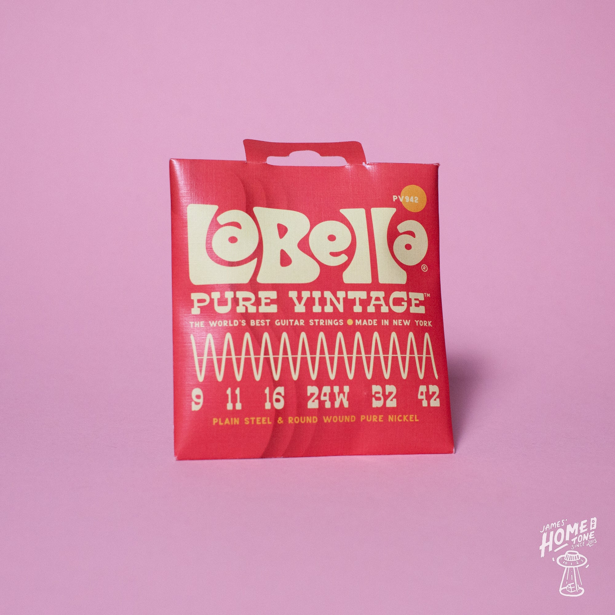 A pack of La Bella Pure Vintage electric guitar strings with gauge sizes displayed on the packaging, placed against a pink background.
