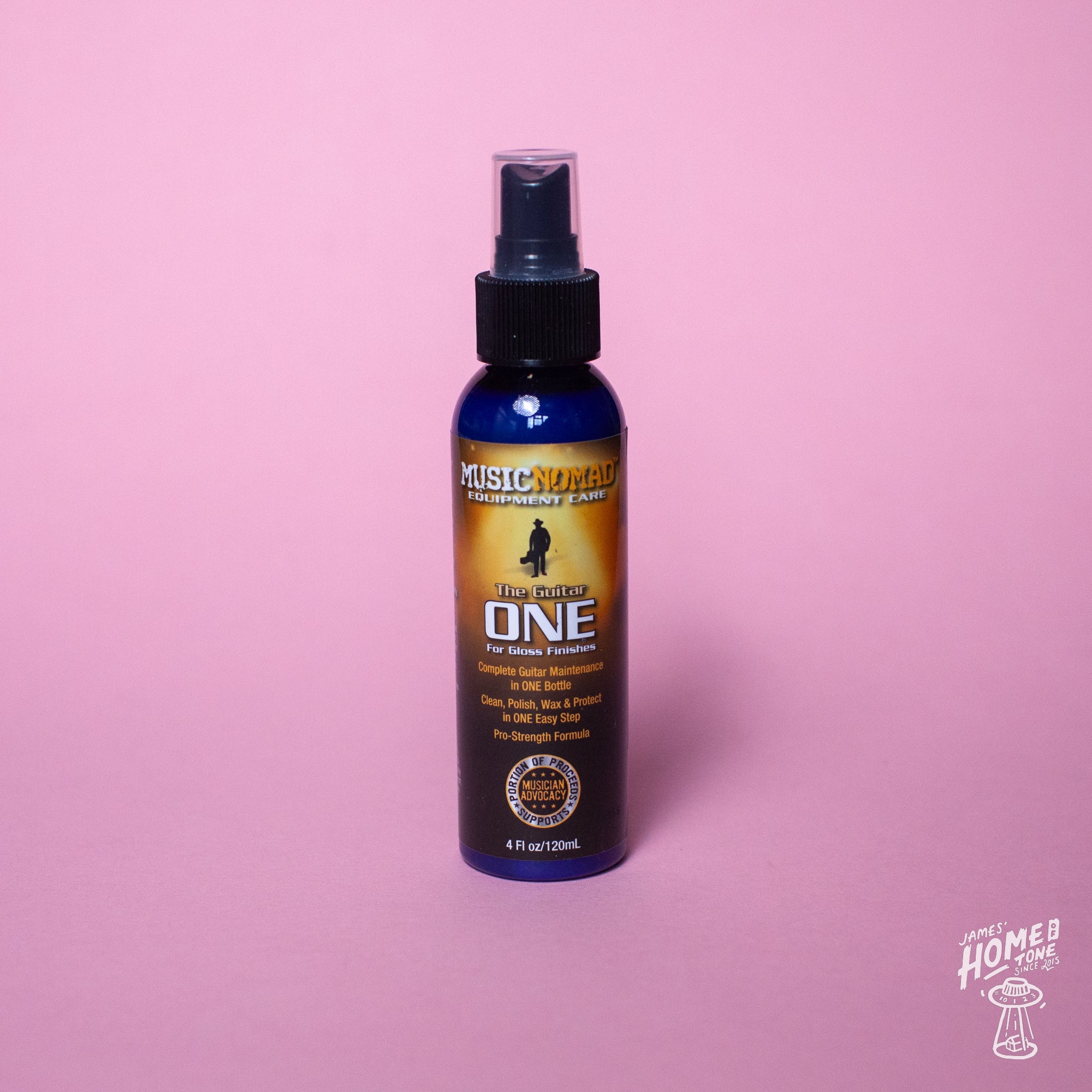A spray bottle labeled 'Guitar ONE' by MusicNomad, designed for cleaning, polishing, and waxing gloss finishes on guitars. The bottle is on a pink background.