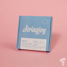 A pack of Stringjoy Orbiters coated nickel wound electric guitar strings with balanced light gauge, displayed against a pink background.