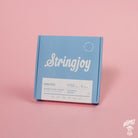 A blue box of Stringjoy Orbiters coated nickel wound electric guitar strings with balanced medium gauge indicated on the packaging.