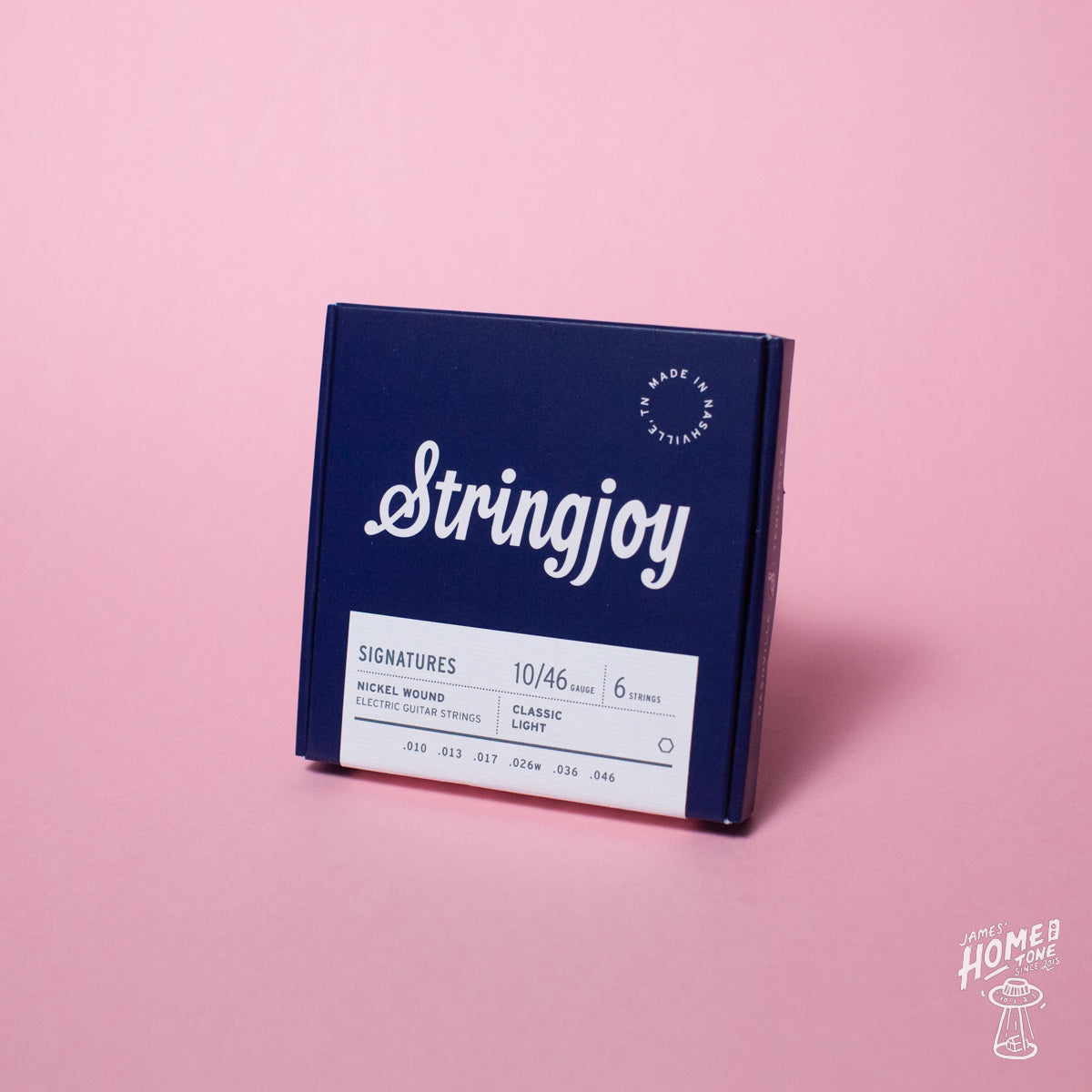 A box of Stringjoy Signature nickel wound electric guitar strings in Classic Light 10-46 gauge, placed against a pink background.