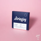 A box of Stringjoy Signature nickel wound electric guitar strings in Husky Super Light gauge, displayed against a pink background.
