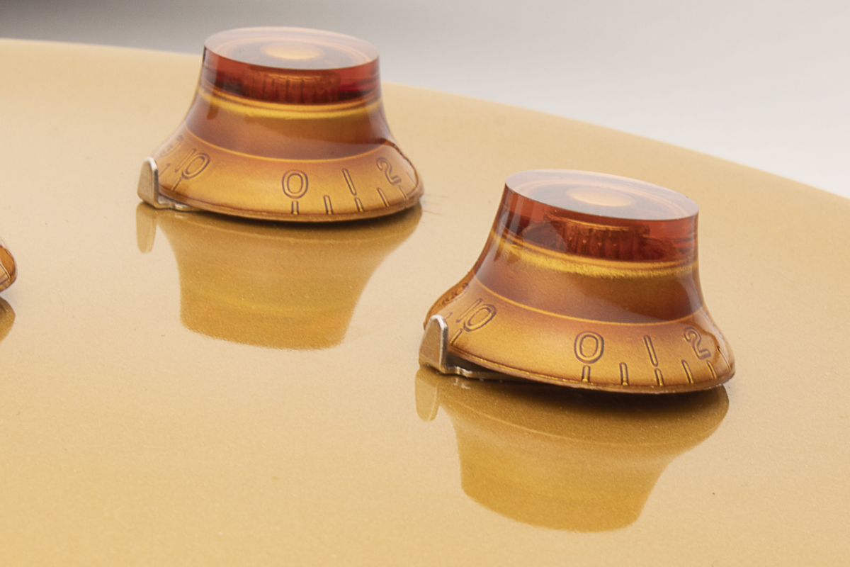 Two amber-colored knobs on a Gibson style guitar with pointer washers installed