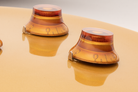 Two amber-colored knobs on a Gibson style guitar with pointer washers installed