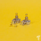 Two brass pot sleeves designed to convert split shaft pots to solid shaft pots, displayed on a yellow background.