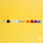 A selection of colored skirted control knobs arranged in a line on a yellow background, designed to fit 1/4" shaft pots.