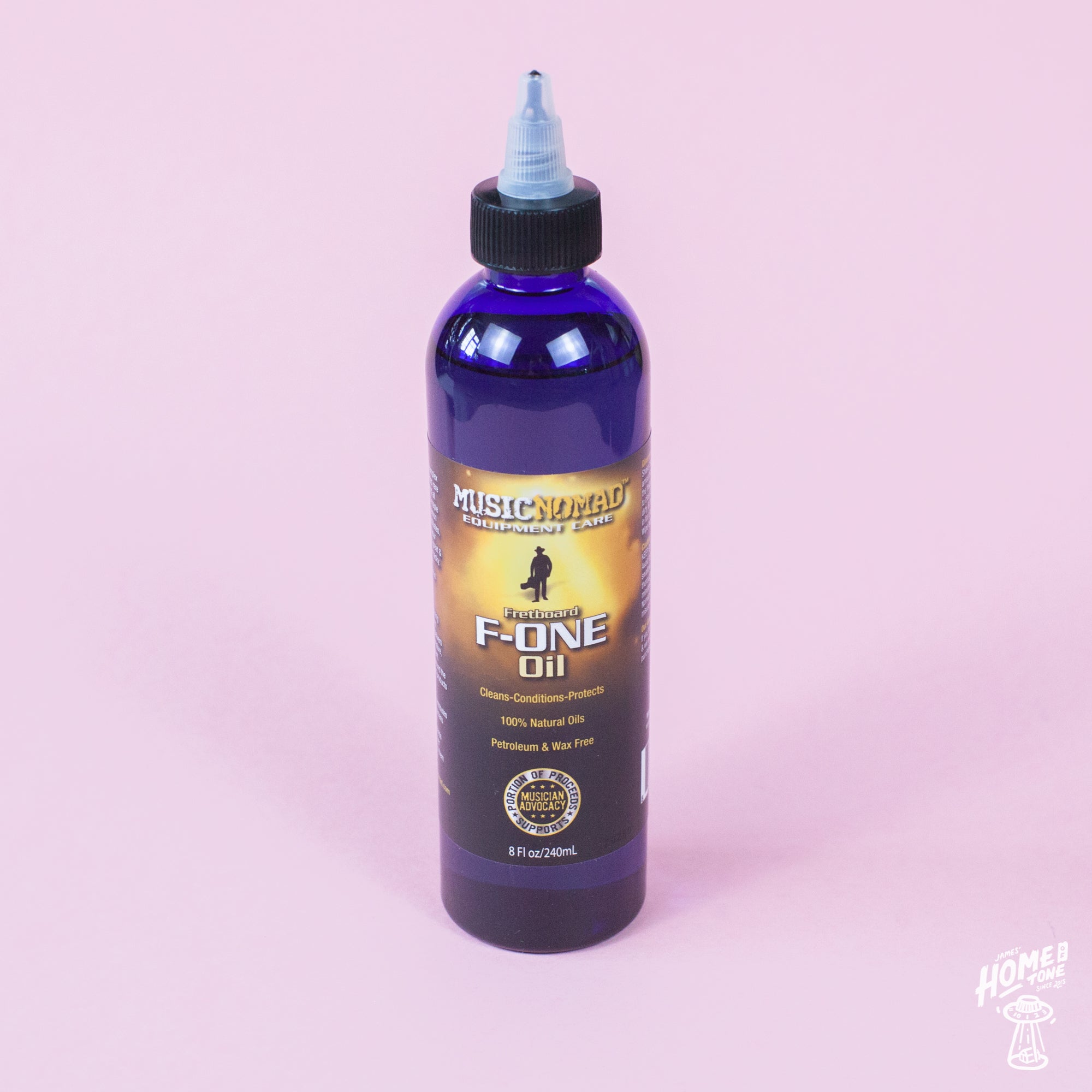 A bottle of MusicNomad Fretboard F-One Oil Cleaner & Conditioner with a blue label on an pink background.