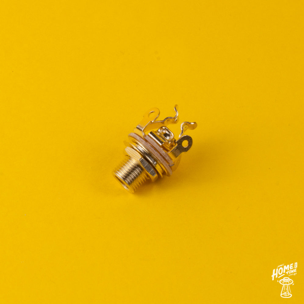 Gold finish, pure tone multi contact mono jack socket for guitars and basses, displayed on a yellow background.