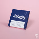 A box of Stringjoy Signature nickel wound electric guitar strings with balanced light plus gauges, displayed against a pink background.