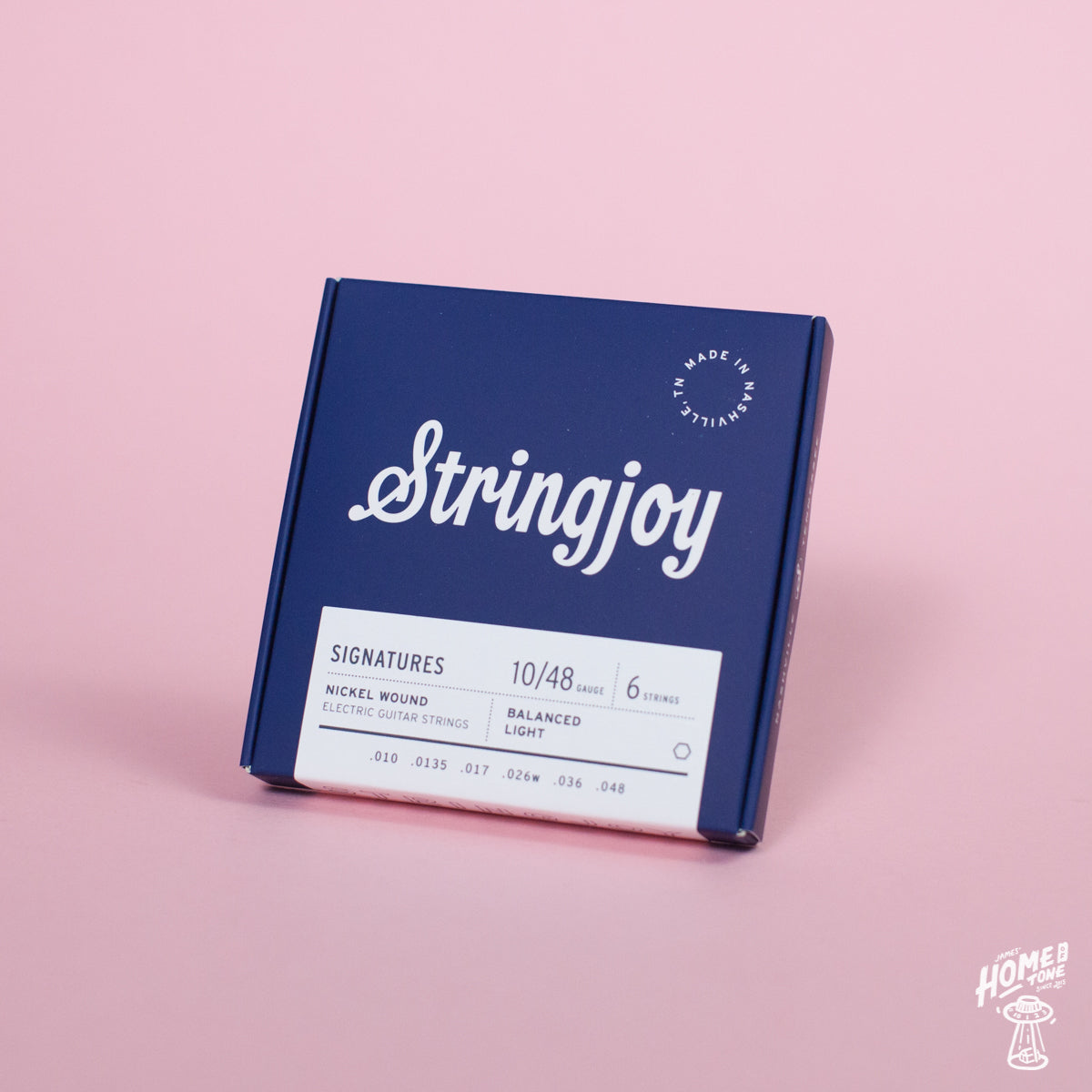 A box of Stringjoy Signature nickel wound electric guitar strings in balanced light gauge, displayed against a pink background.