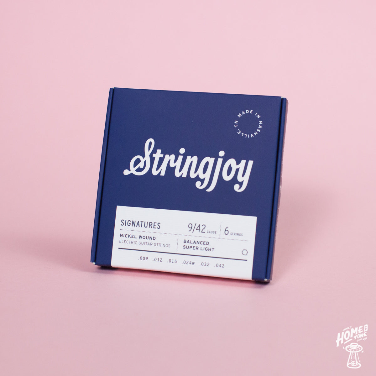 A box of Stringjoy Signature nickel wound electric guitar strings with balanced super light 9-42 gauges on a pink background.
