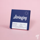 A box of Stringjoy Signature nickel wound electric guitar strings with balanced super light 9-42 gauges on a pink background.