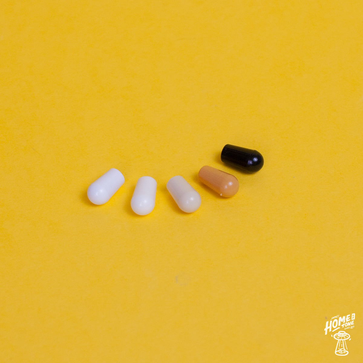 A selection of switch tips suitable for Switchcraft USA toggle switches in white, cream, antique white, black or amber. Placed on a yellow background with the Home of Tone logo in the corner.