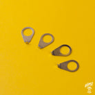 Three nickel pointer washers on a yellow background, typically used for adjusting control knobs on musical instruments.